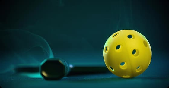 Yellow pickleball and paddle on a court